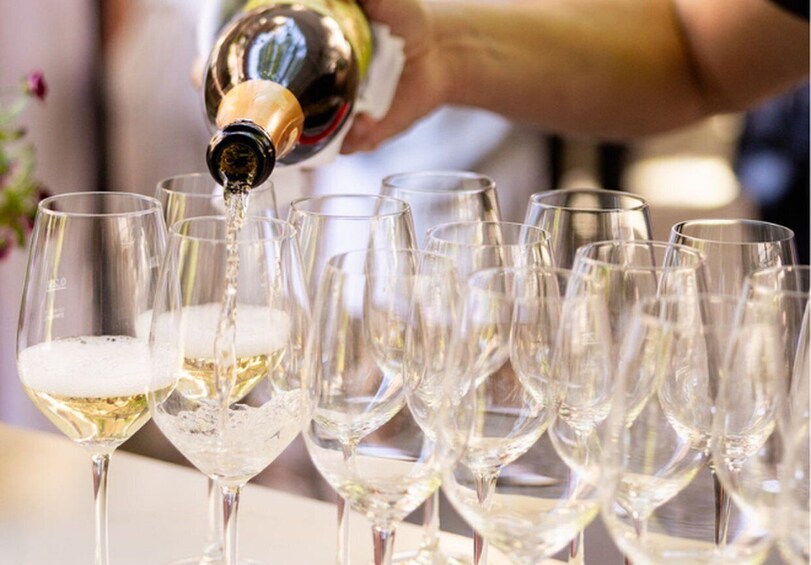 A person pouring champagne into several glasses. 2