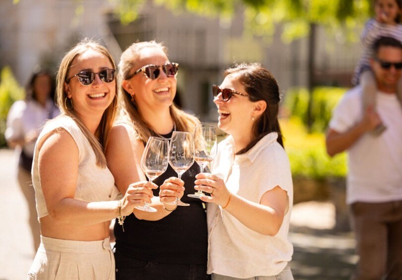 Three people toasting with wine glasses outdoors. 1