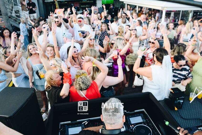 A crowded outdoor event with people dancing and raising their hands. 2