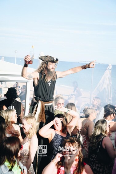 A person in a pirate costume standing on a boat, surrounded by a crowd of people. 1