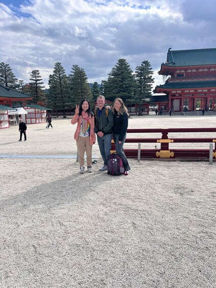 A group of people posing in front of traditional architecture with a clear sky and trees in the background. 2