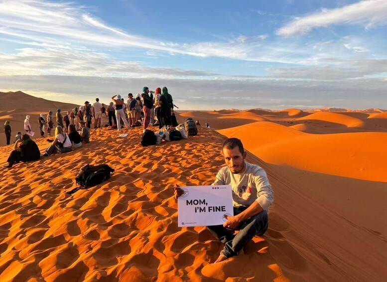 Paesaggio desertico con dune di sabbia e un gruppo di persone sedute e in piedi. 4