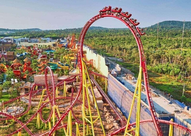 A roller coaster with multiple tracks and a steep drop, surrounded by greenery and buildings. 5