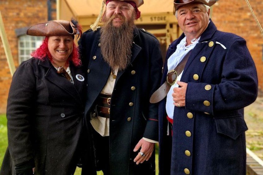 Three people in historical costumes standing in front of a building. 2