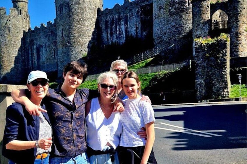 A group of people standing in front of a historic castle with stone walls and towers. 3