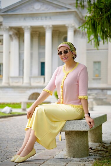 A person sitting on a bench in front of a classical building with columns. 2
