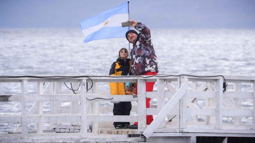 A person holding a flag on a pier with a body of water in the background. 5