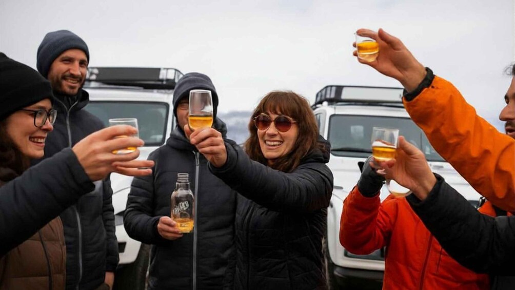 A group of people toasting with drinks in a parking lot. 1