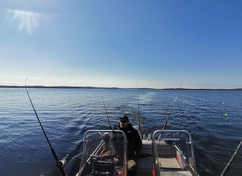 A person fishing on a boat with calm water and a clear sky. 5