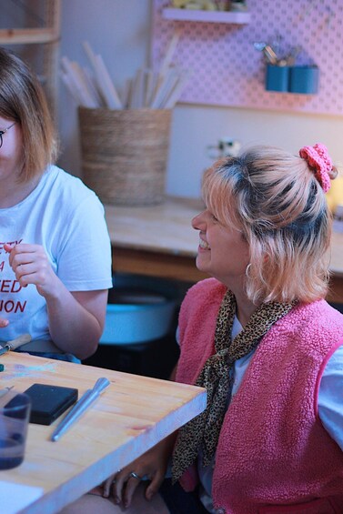 Two people sitting at a table with a smartphone, a pen, and a notebook. 5