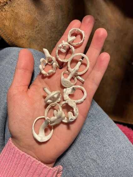 A hand holding several white, twisted metal objects. 2