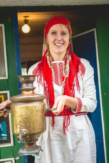 A person holding a brass samovar. 2