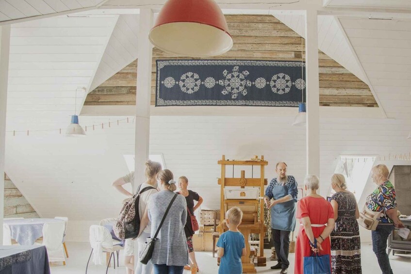 A group of people in a spacious room with high ceilings and exposed wooden beams, observing an exhibit. 5