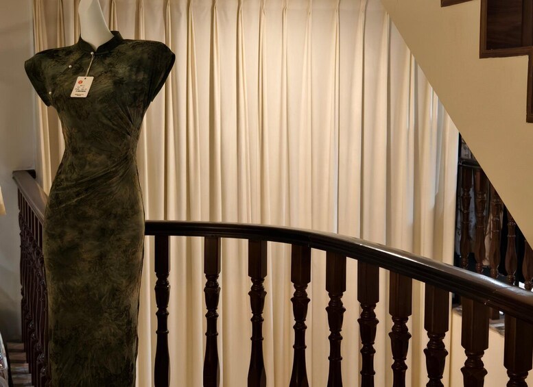 A mannequin in a dress in a room with a staircase and curtains. 4