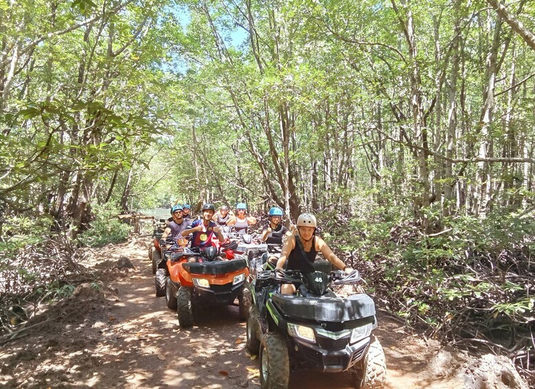 A group of people on ATVs in a forested area. 2