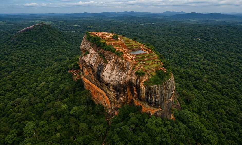 A large rock formation with terraced structures and a dense forest surrounding it. 1