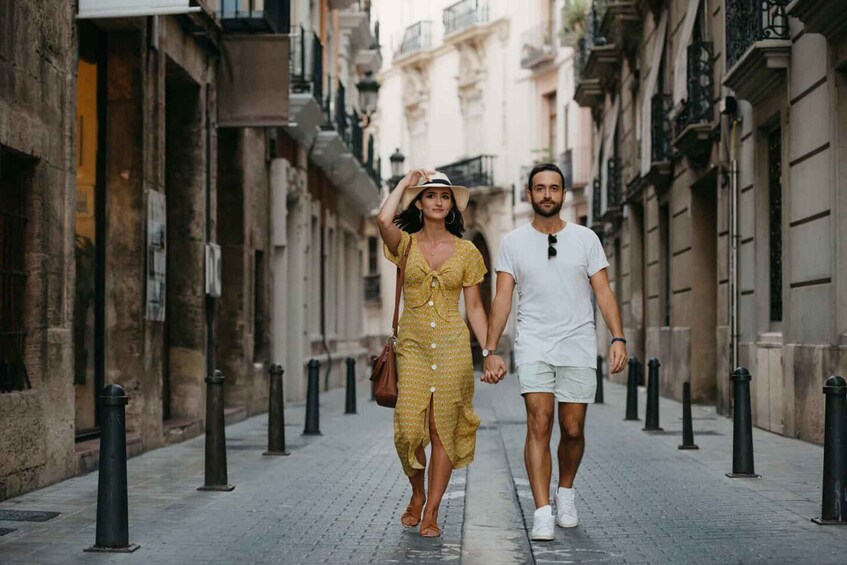 A couple walking down a narrow urban street lined with historic buildings. 4