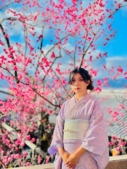 A person in traditional attire standing in front of cherry blossoms. 2