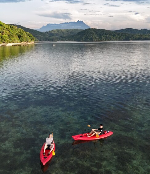 Two people kayaking on a calm lake with mountains in the background. 2
