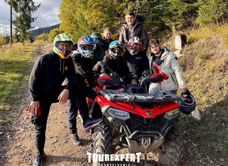 A group of people with ATVs on a dirt path surrounded by trees. 1