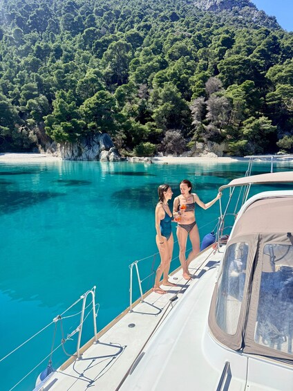 Two people on a boat in a turquoise sea with a forested coastline. 5