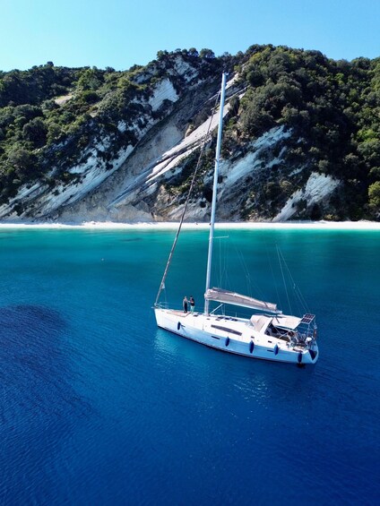 A sailboat on turquoise waters with a mountainous coastline in the background. 2