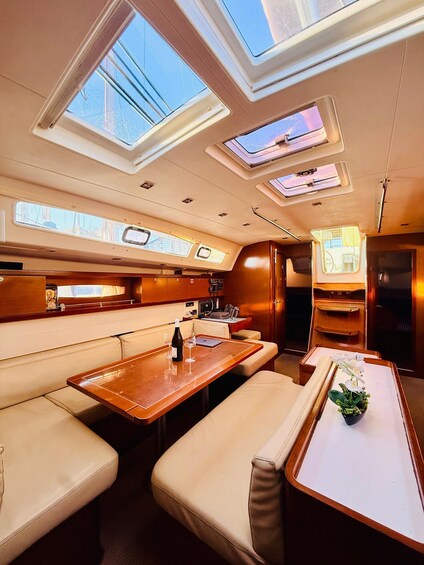 A yacht interior with a dining area, cushioned seating, and skylights. 4