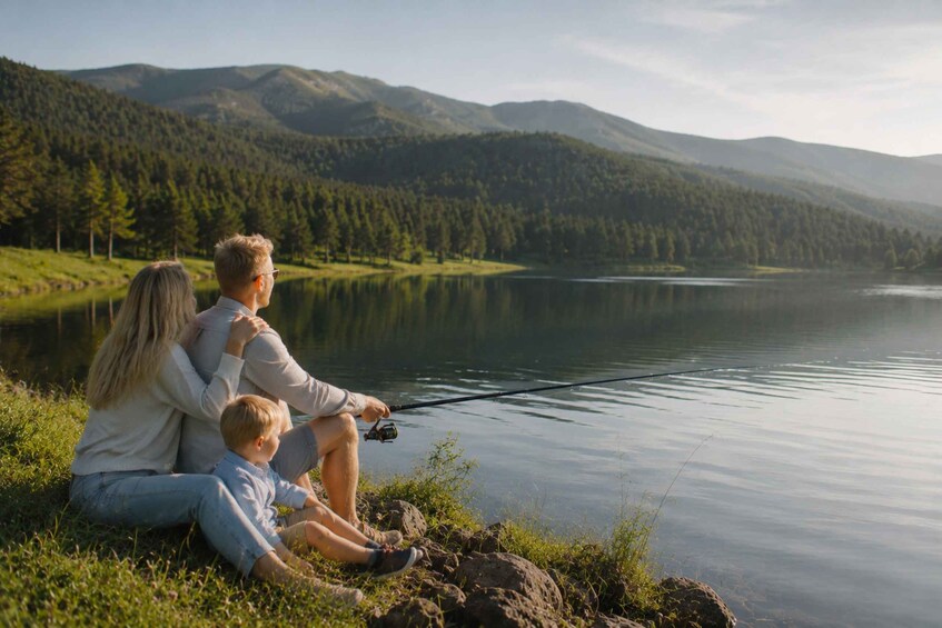 A family fishing by a calm lake with mountains in the background. 2