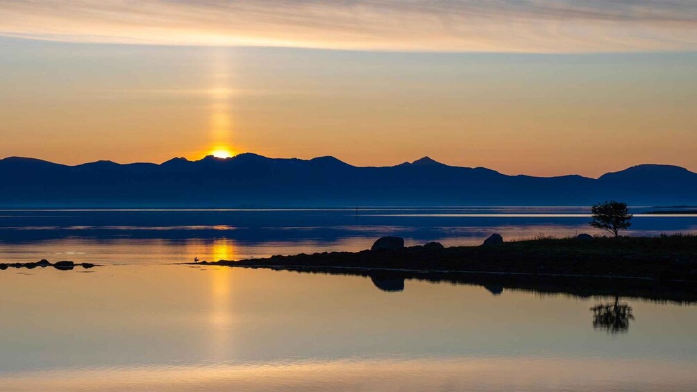 A sunset over a calm lake with mountains in the background. 3