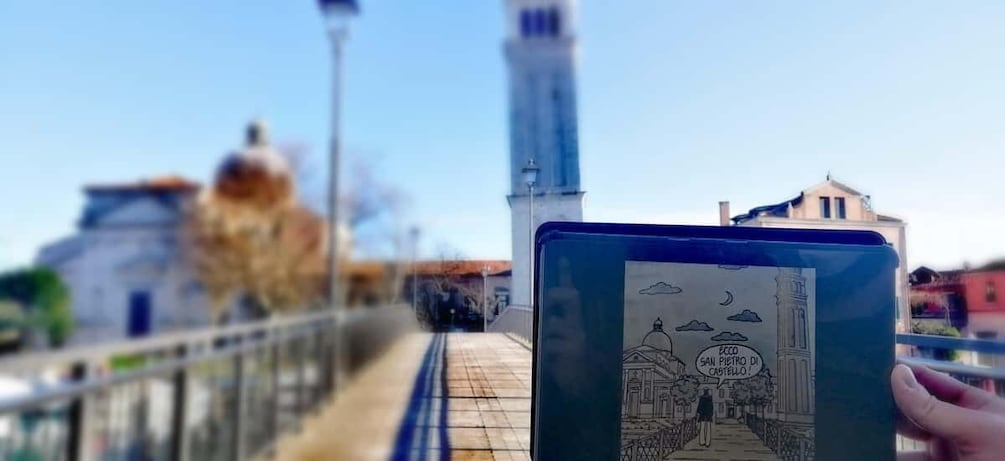 A hand holding a tablet with a drawing of a building, a bridge, and a tower in the background. 2