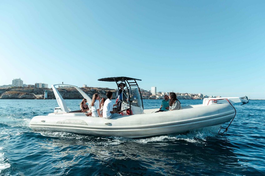 A white inflatable boat with passengers on a clear day, moving on calm water with a coastal cityscape in the background. 3
