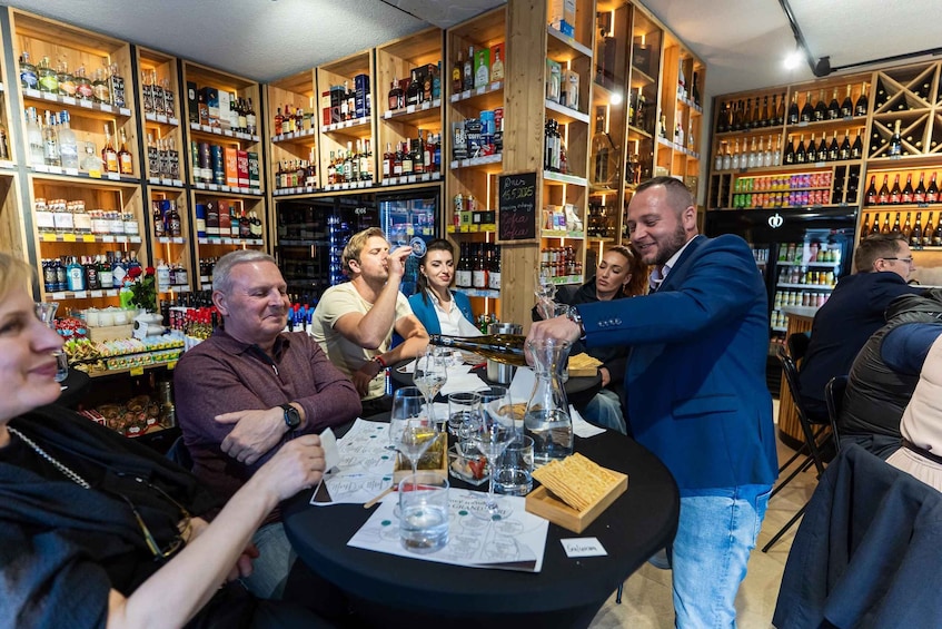 A group of people at a wine tasting event in a well-stocked bar with shelves of various bottles. 3