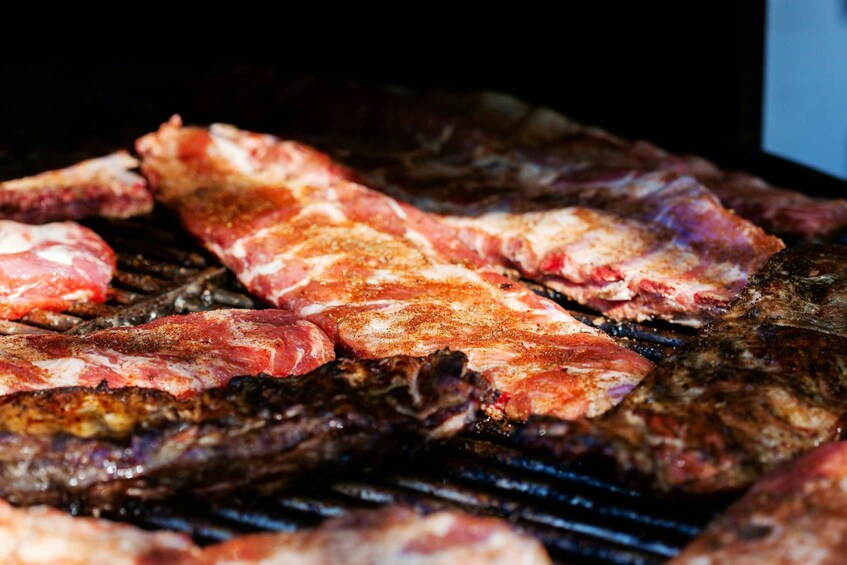 A grill with various cuts of meat being cooked. 2