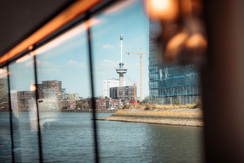A river with a cityscape in the background, including a tower and construction cranes. 1