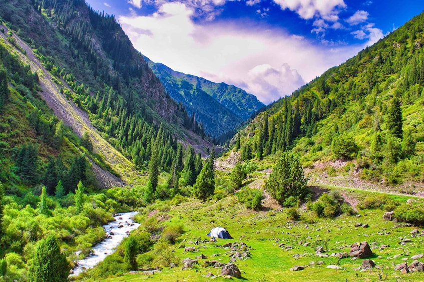 A river flowing through a mountainous valley with a tent and rocky terrain. 3