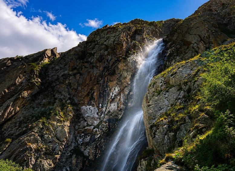 A waterfall cascading down a rocky cliff with lush greenery around. 2