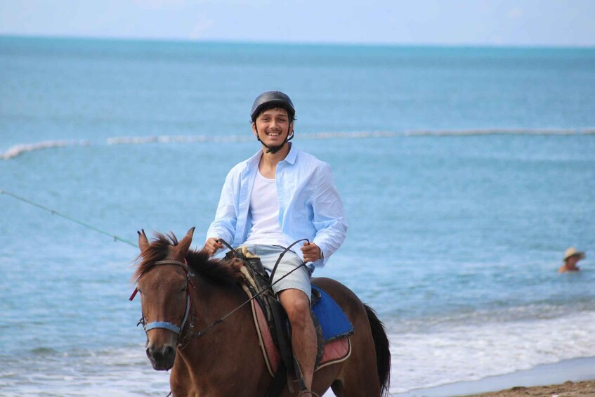 Una persona montando a caballo en una playa, con el océano al fondo. 4