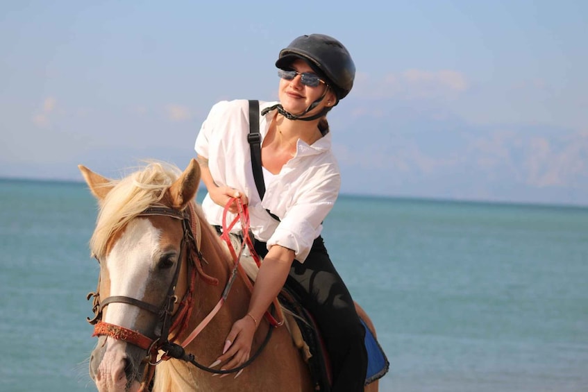 Una persona montando a caballo en una playa, con el océano al fondo. 2