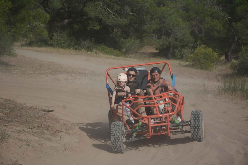 A dune buggy on a dirt path with sparse vegetation and trees in the background. 4