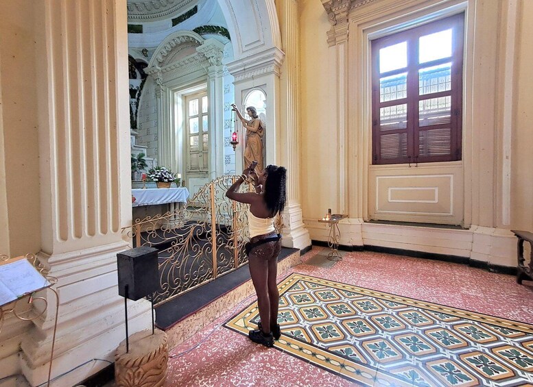A person taking a photo in a room with ornate columns, a patterned floor, and a statue. 5