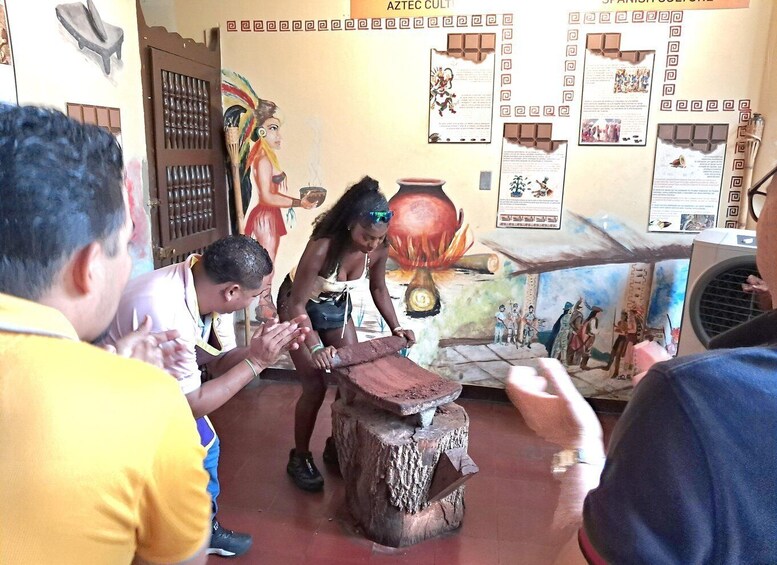A group of people observing a demonstration involving a pot on a wooden stump. 2