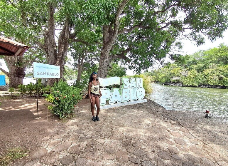 A person standing in front of a 'San Pablo' sign by a river. 4