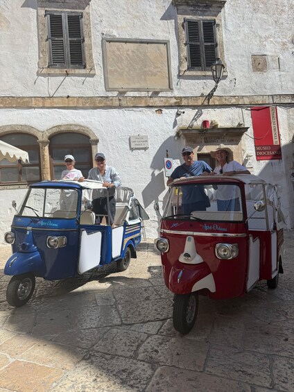 Vintage cars parked on a cobblestone street, with people standing nearby. 3