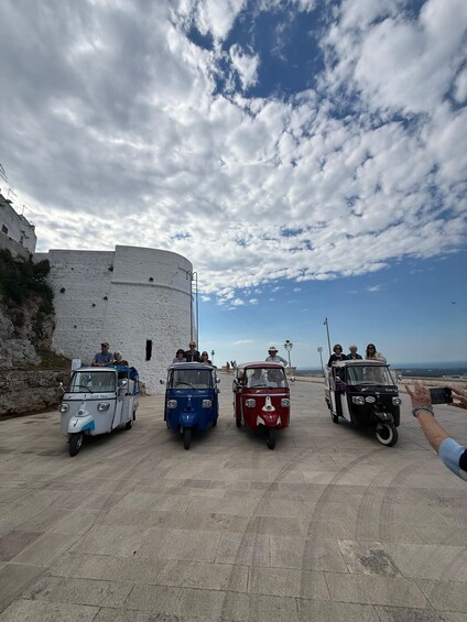 Three vintage city tour vehicles parked in front of a historic fort. 5