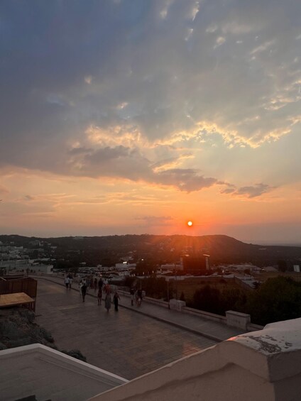 A sunset over a cityscape with people walking on a street. 4