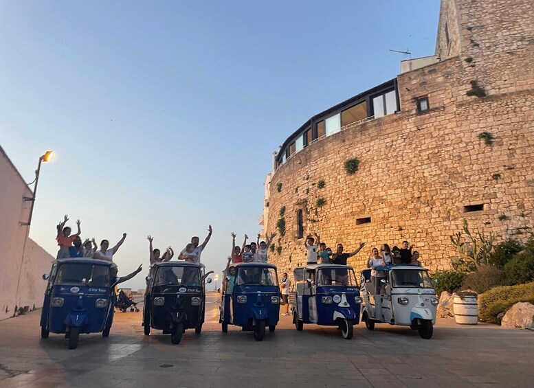 A group of people on tuk-tuks in front of a historic stone building. 3