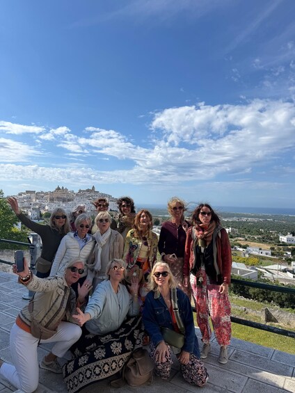 A group of people posing for a photo with a scenic view of a coastal town and the sea in the background. 2
