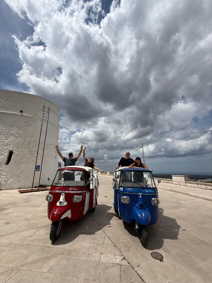 Two vintage cars parked on a paved area with a cloudy sky above. 1
