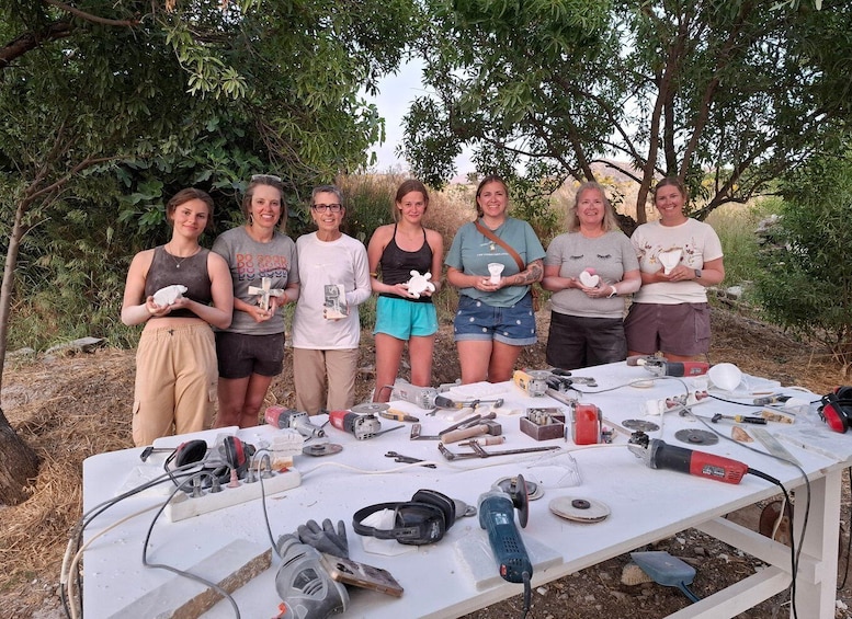 A group of people standing outdoors with tools and materials on a table. 1