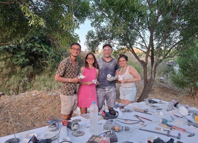 Four people standing outdoors with a table of tools and materials in front of them. 4